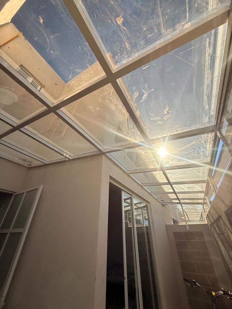 Interior hallway with glass and metal frame skylight ceiling allowing sunlight to flood the narrow passage below