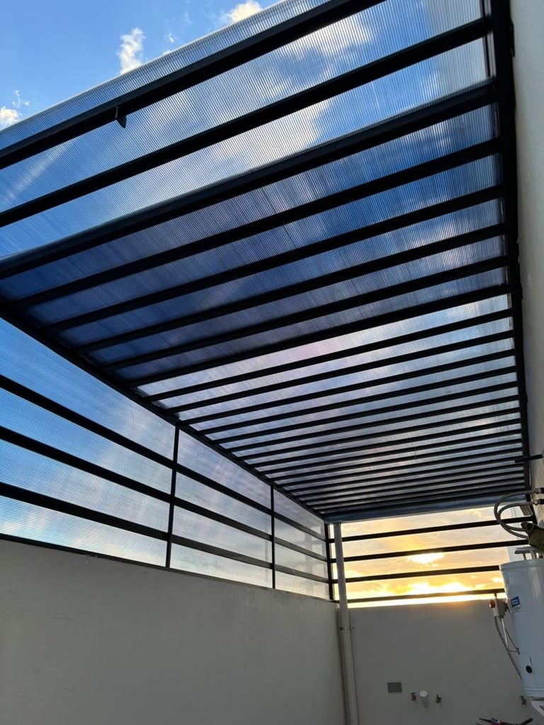 Polycarbonate pergola or patio cover with black metal frame beams against blue sky with clouds