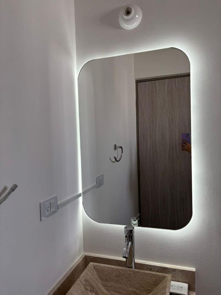 Modern bathroom with illuminated LED mirror, round sink, and wall-mounted camera above