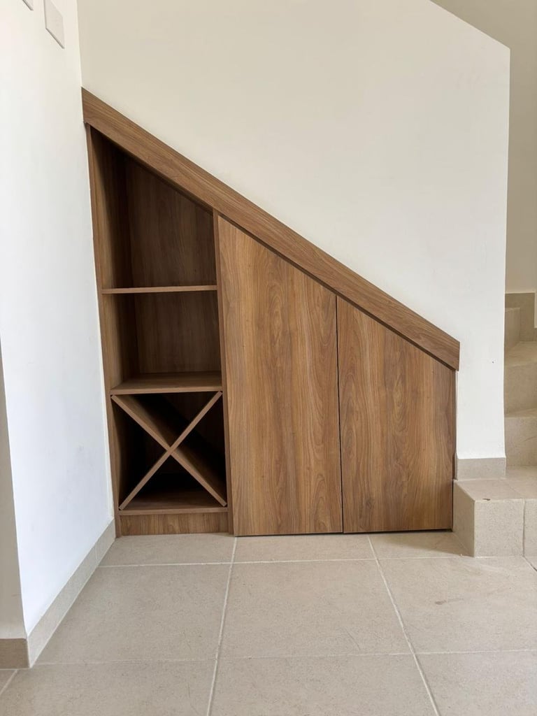 Built-in wooden storage cabinet with open shelving and closed doors under a sloped ceiling in a modern room with tile flooring