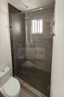 Modern bathroom with glass-enclosed shower stall and white toilet visible on left side