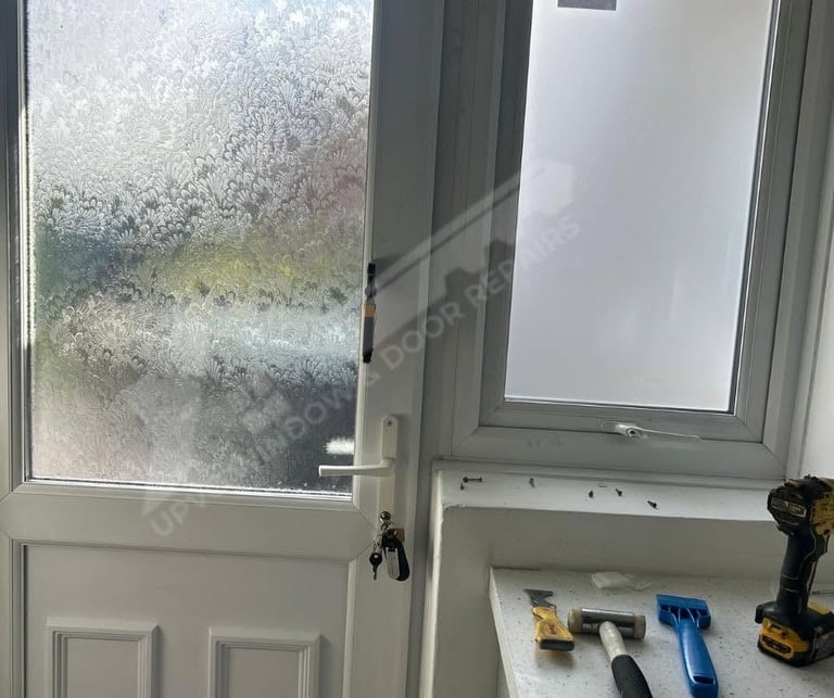 Two white exterior doors with frost-covered glass panes, tools and equipment scattered on the floor below
