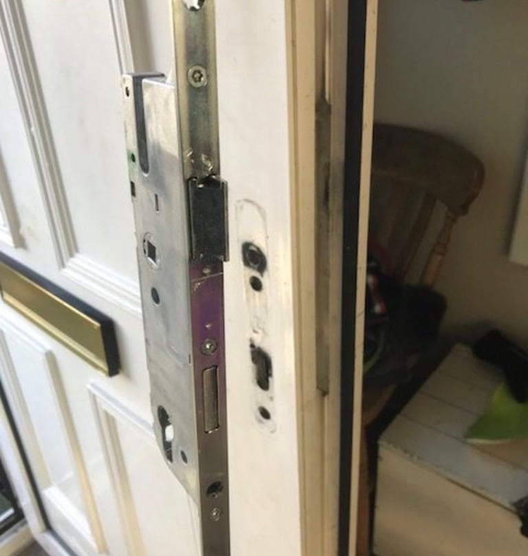 Close-up of open door frame showing latch mechanism and interior view of room with furniture