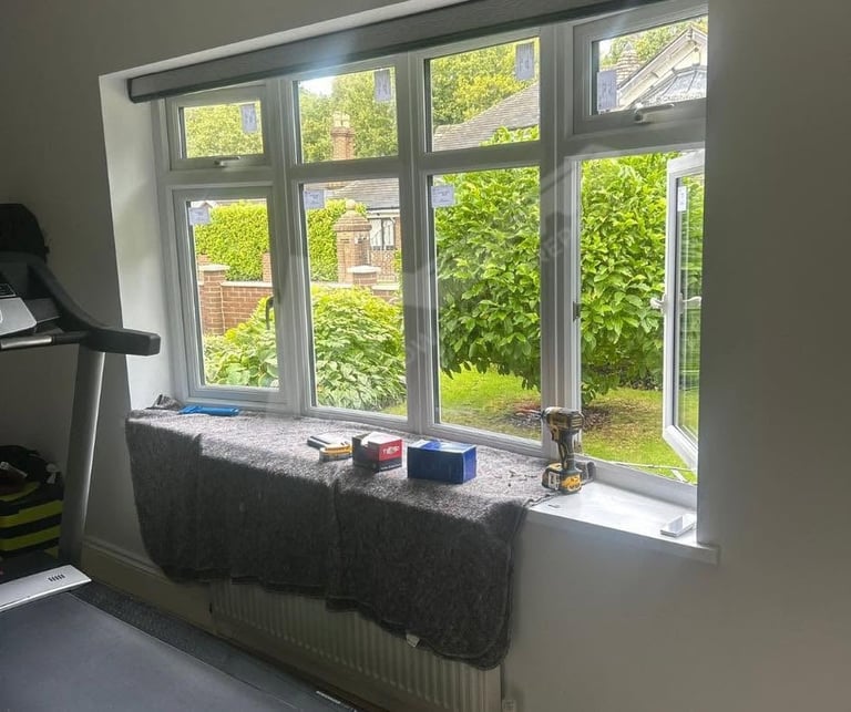 Large multi-pane window with garden view, windowsill with items and exercise equipment visible to the left