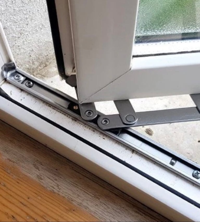 Close-up of a hinged bracket or hinge mechanism on a white window frame