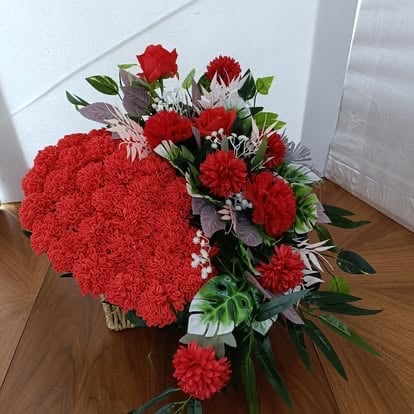 Duża czerwona kompozycja z poduszką z goździków w kształcie serca i mieszanymi czerwonymi kwiatami w przezroczystym wazonie