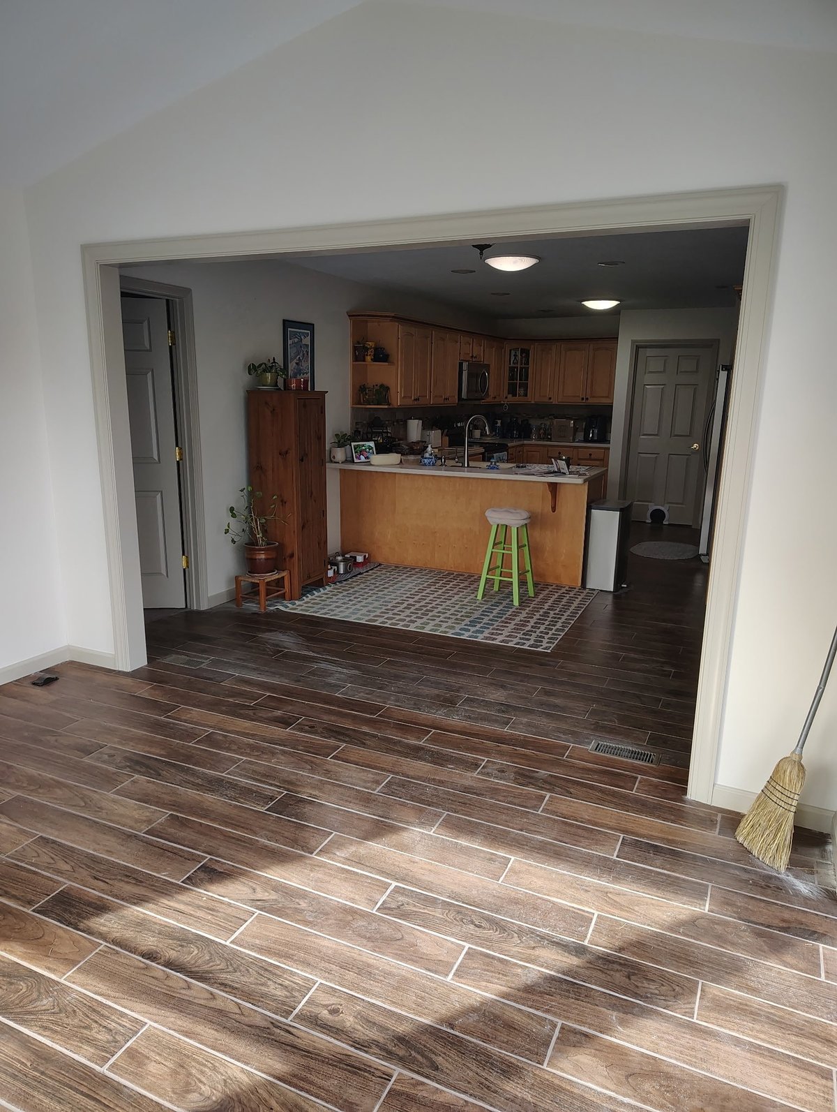 Open plan kitchen and living room with wood flooring, brown cabinetry, and white walls viewed from entryway