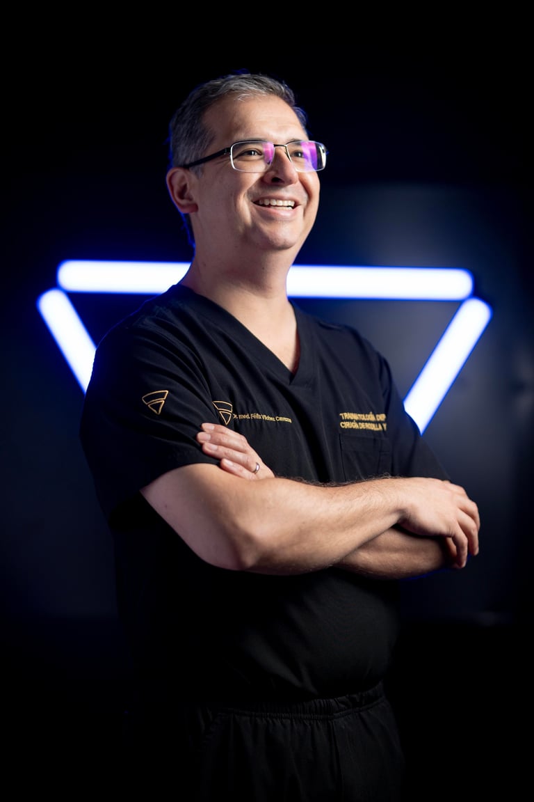Professional man wearing glasses and black scrubs with arms crossed, smiling confidently against a dark background with neon blue geometric lighting.