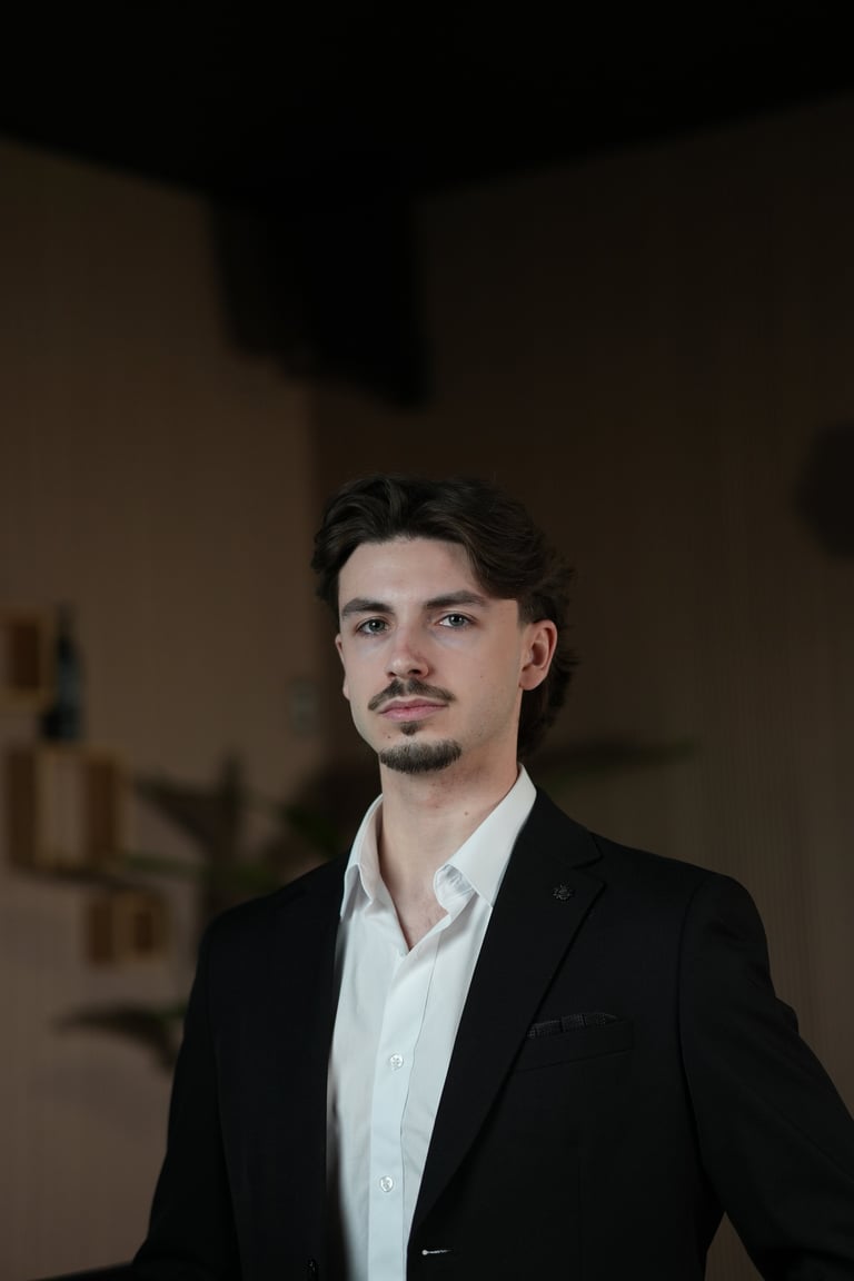 Cory Clairoux — Man with dark hair and facial hair wearing a black blazer and white shirt against a neutral background