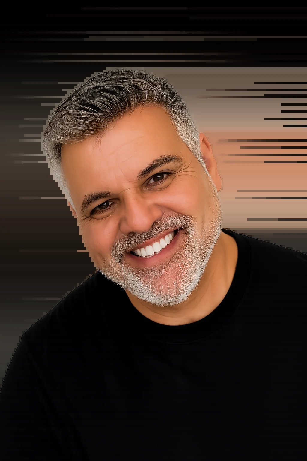 Retrato cercano de Neelesh Babalawo, hombre sonriente de mediana edad con cabello entrecano y barba, usando playera negra