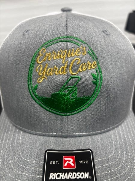 Gray cap with green embroidered emblem made for a local yard care business