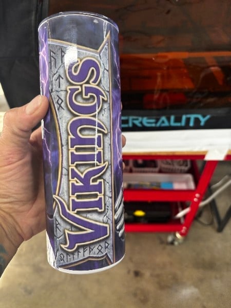 Custom wrapped tumbler with team design held in hand