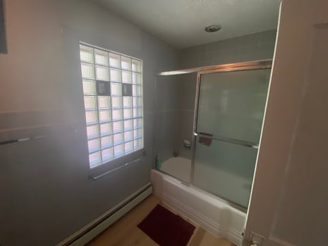Modern bathroom with glass block window, frameless glass shower enclosure, and white tiled bathtub surround