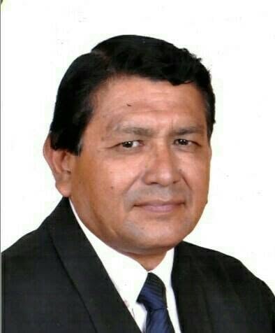 Professional headshot of a middle-aged man wearing a dark suit and blue tie against a white background