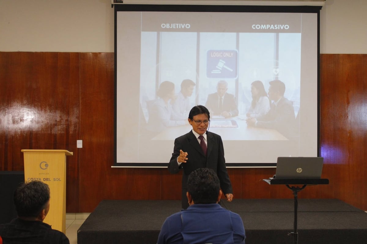 Man in business suit presenting at podium with projector screen showing office meeting comparison slide behind him