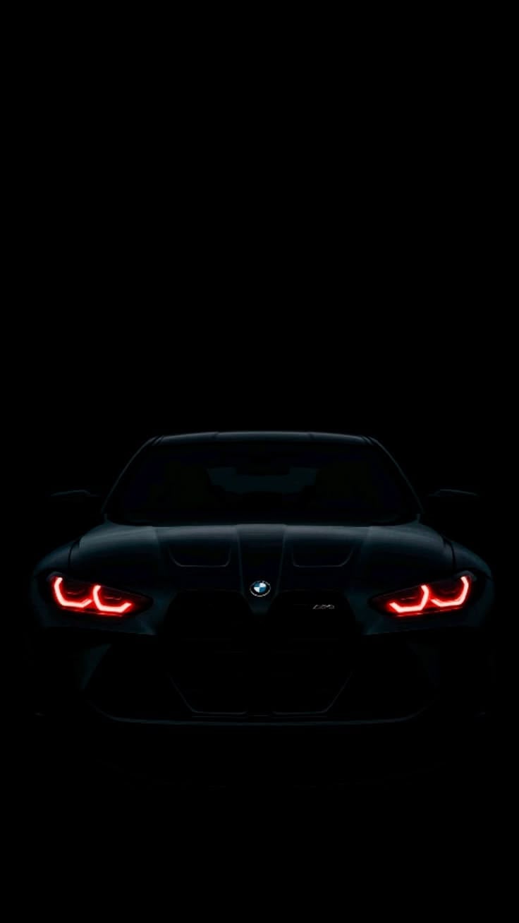 Front view of a black BMW sports car with glowing red LED taillights against a dark background
