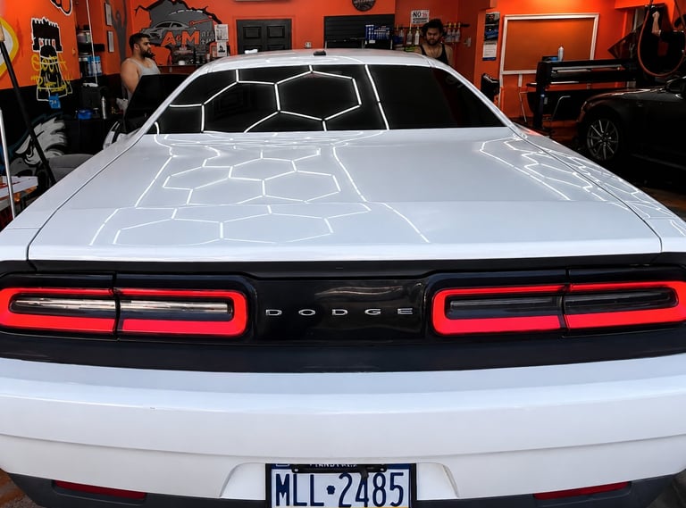 White Dodge Challenger rear view with red LED taillights in orange-walled garage