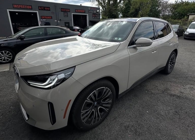 White compact SUV parked at car dealership lot with service garage building in background