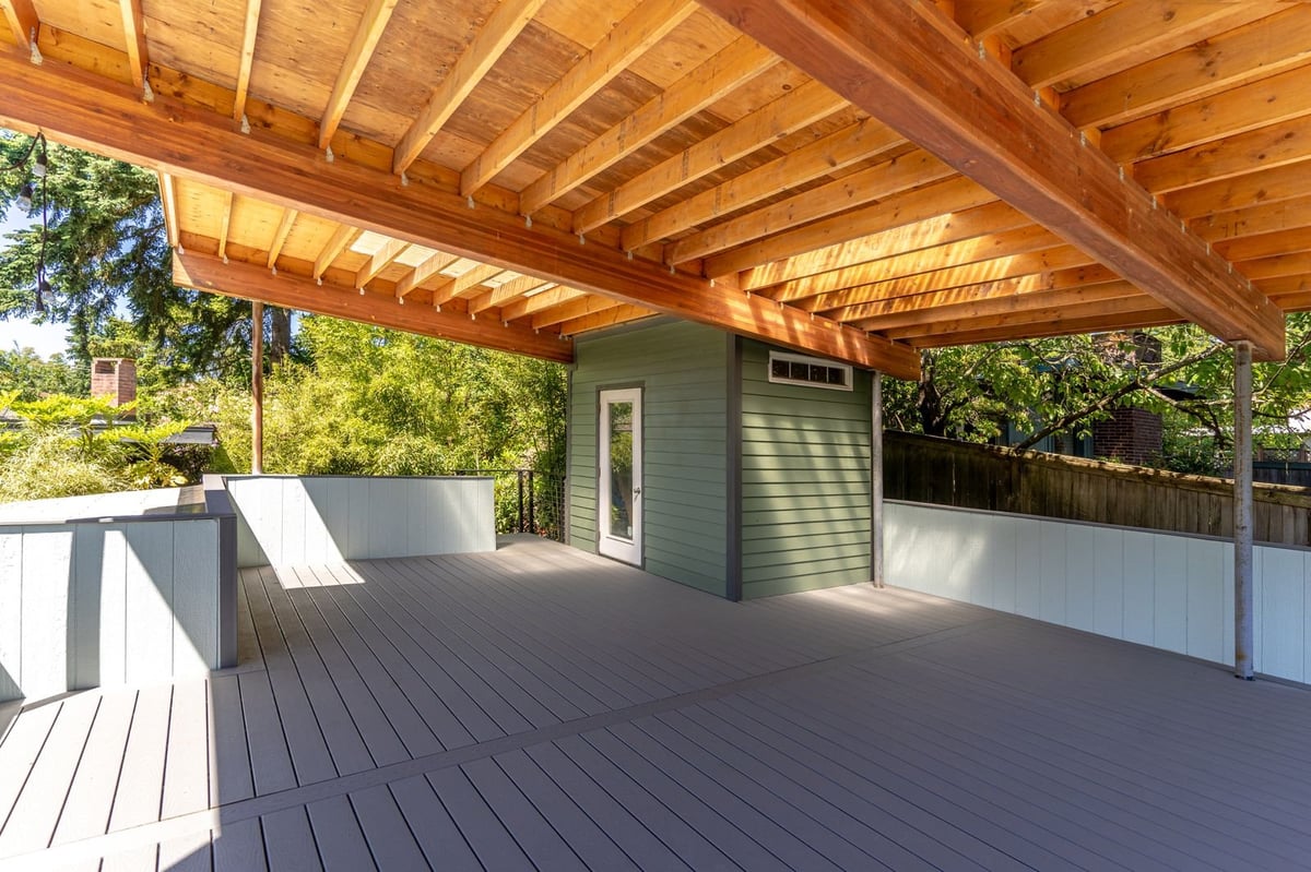 Modern covered deck with wooden beam ceiling and dark composite decking
