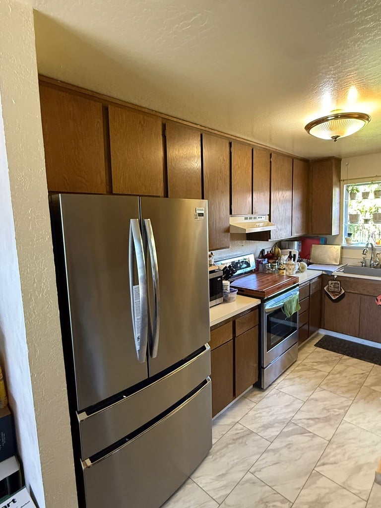 Galley kitchen with wood cabinets, stainless steel appliances, and butcher block range before renovation