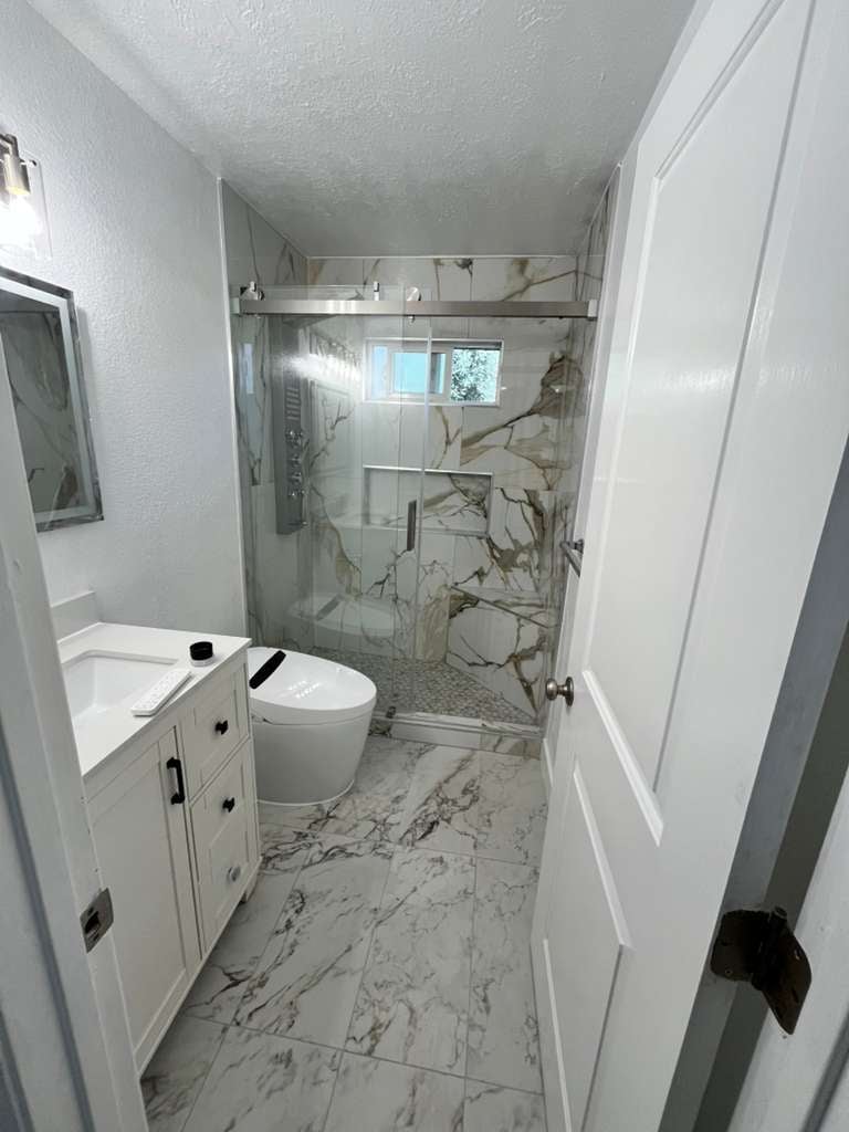 Modern bathroom with white vanity, toilet, and marble tile shower