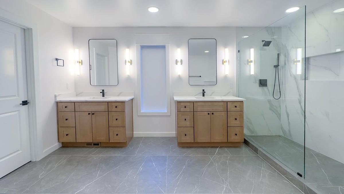 Modern master bathroom with dual vanities, marble floors, and large walk-in shower