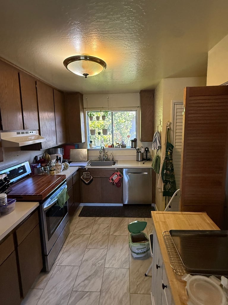 Galley kitchen with dark wood cabinets, stainless steel appliances, and marble tile flooring before renovation