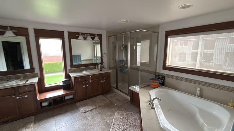 Spacious dated bathroom with dark wood vanities and corner soaking tub