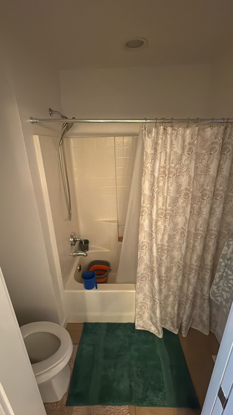 Dated bathroom with beige shower curtain and bathtub