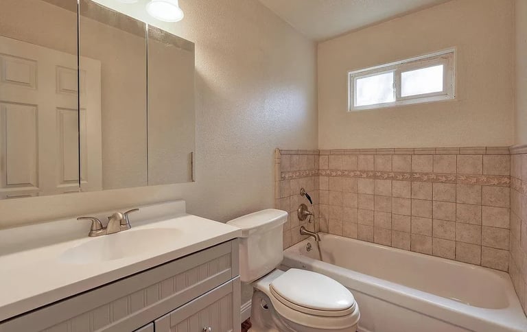 Dated bathroom with pink tile tub surround before remodel