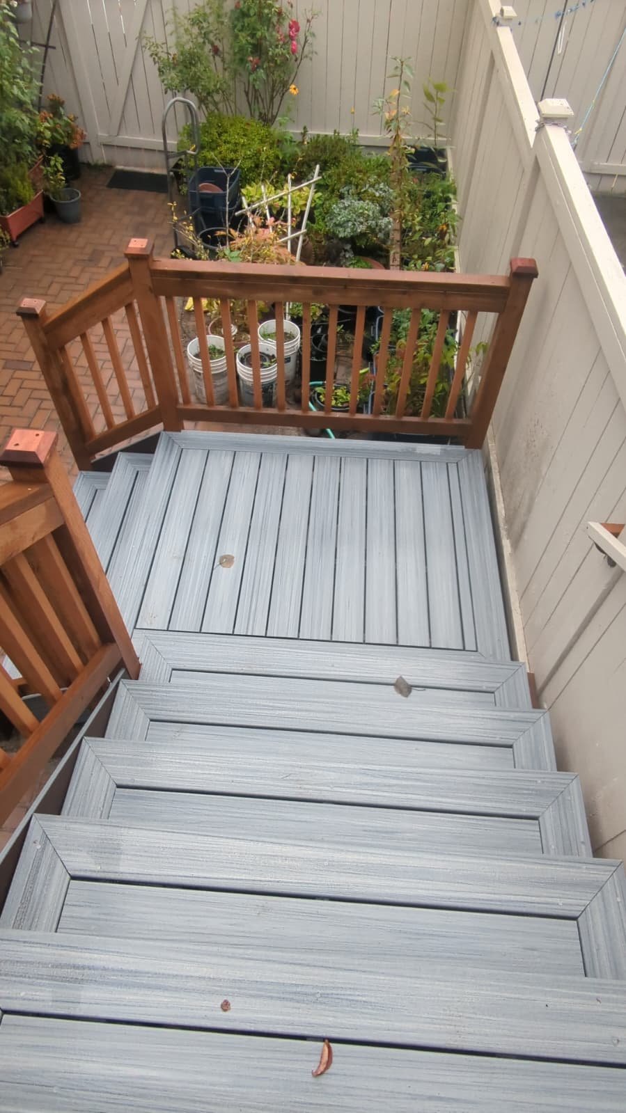Elevated wooden deck with new gray composite stairs and cedar railing