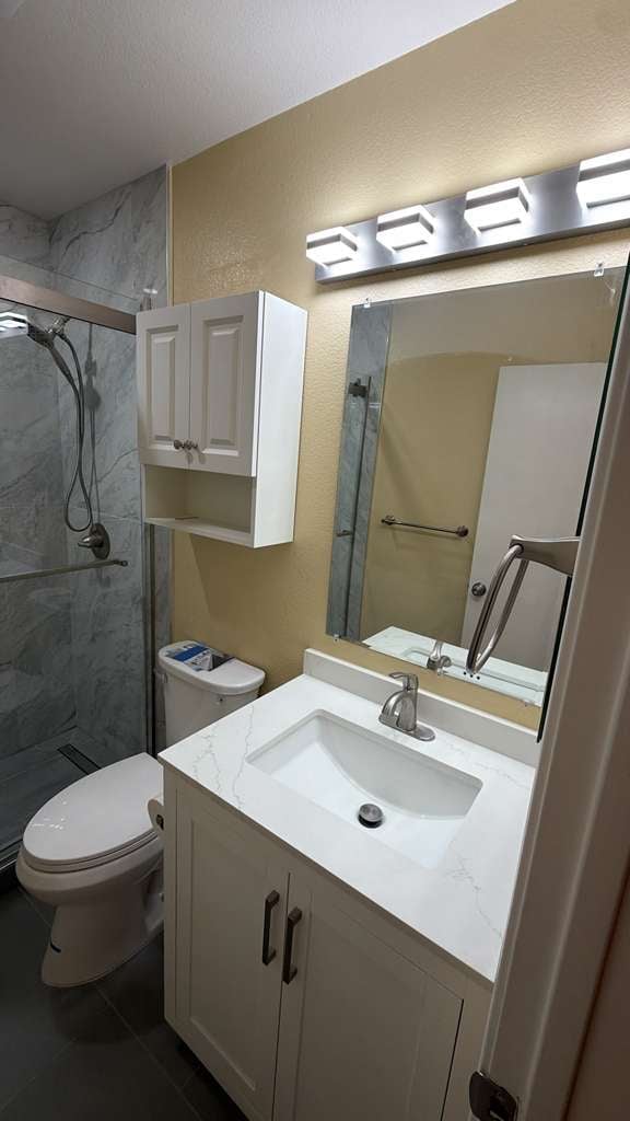 Modern bathroom with white vanity, large mirror, and dark tile shower