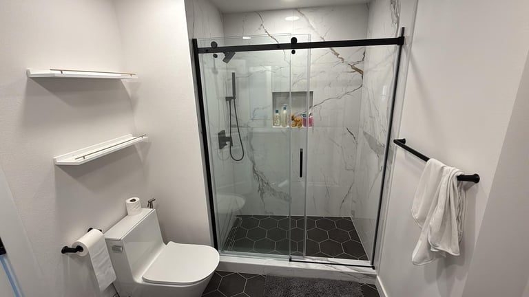 Modern bathroom with walk-in shower, glass doors, and dark tile flooring