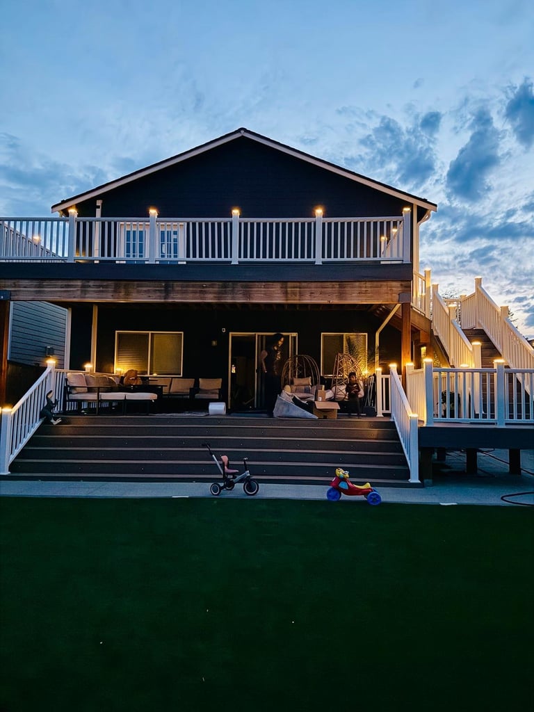 Modern two-story dark house with illuminated deck at dusk