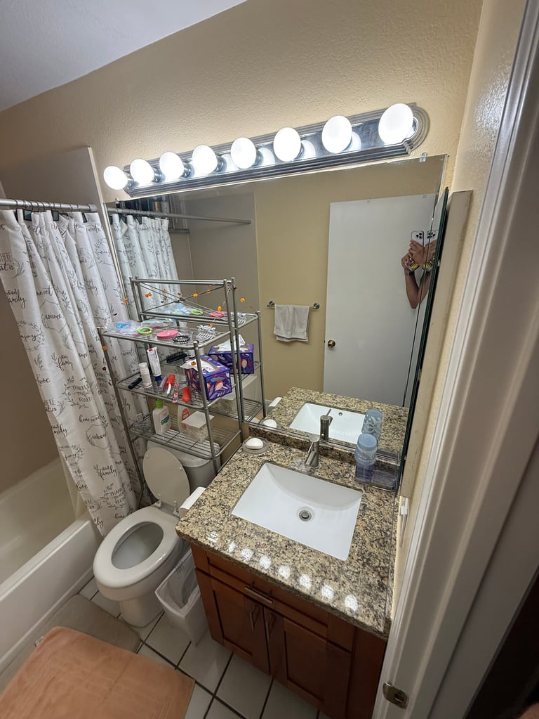 Bathroom with dated vanity, mirror, and granite countertop