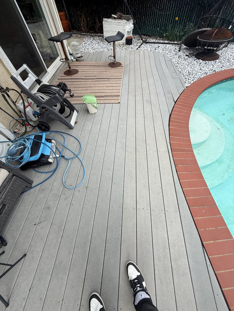 Person on worn wooden deck with pool and cleaning equipment