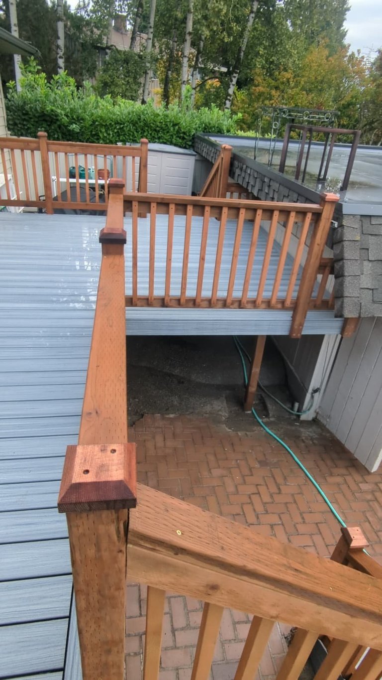 New wooden deck with fresh brown railings overlooking brick patio