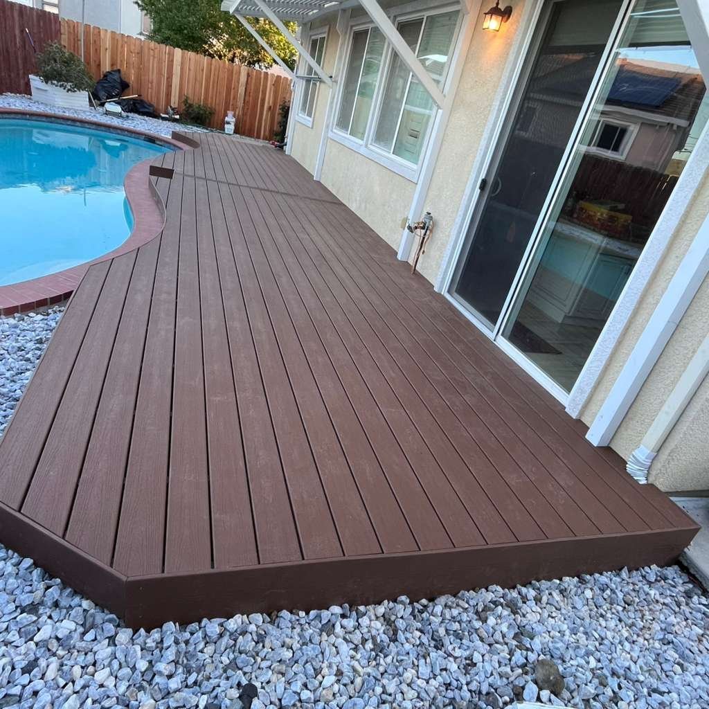 New dark brown composite deck with white railing next to swimming pool
