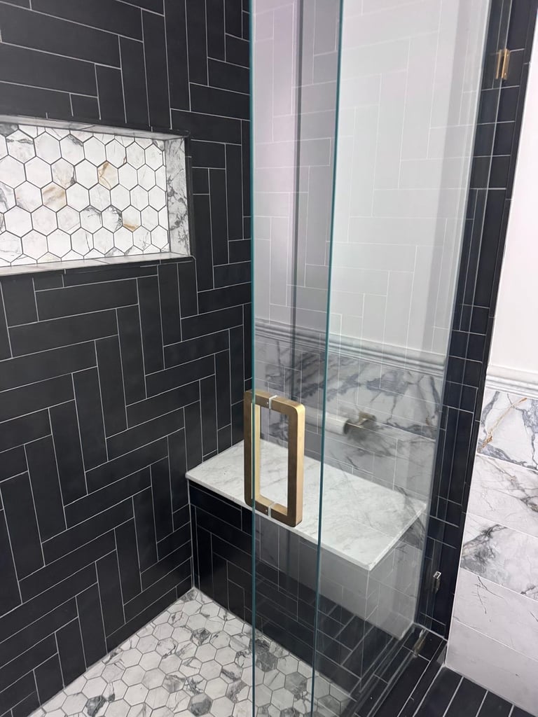 Black herringbone shower with glass door and gold handle