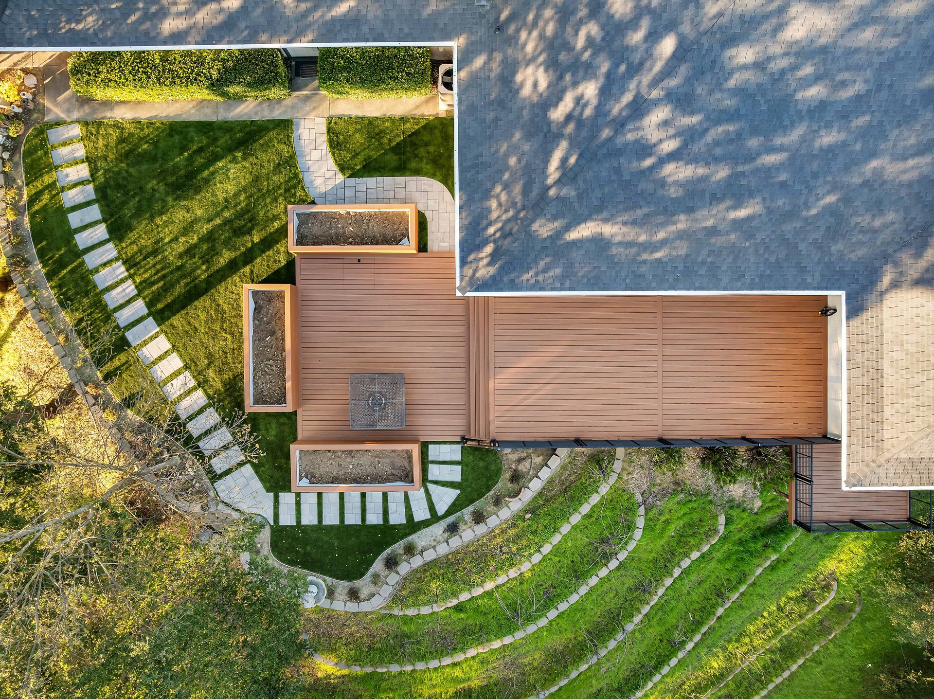Aerial view of a modern home with composite deck, curved walkways, and landscaped grounds