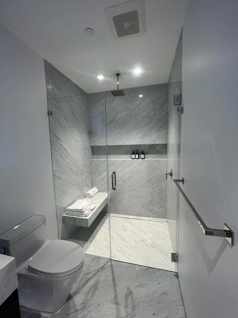 Marble walk-in shower with glass enclosure, revealing what sits behind a bathroom's finished surfaces
