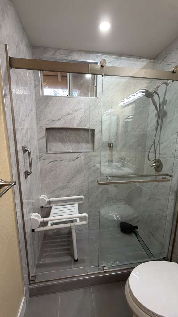 Modern bathroom shower with marble tile walls and glass sliding door