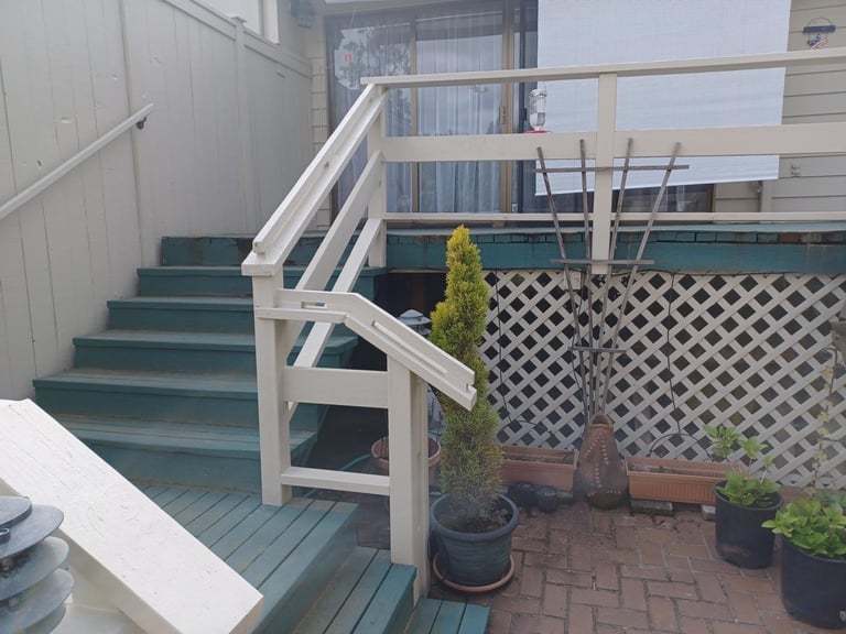 Exterior wooden deck with peeling green stairs
