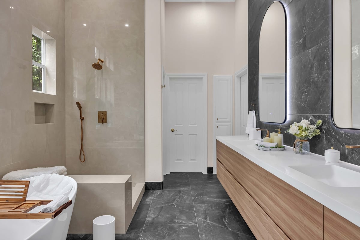 Modern bathroom with wood vanity, dark tile accents, and walk-in shower