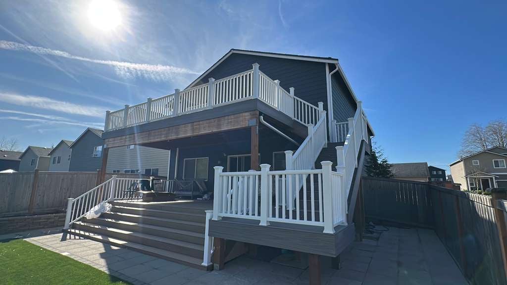 New two-story house with white railings and wooden deck