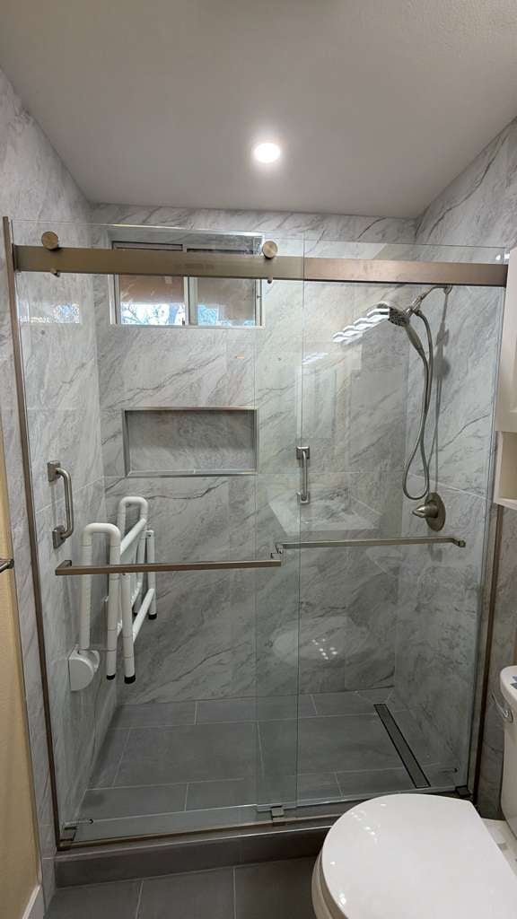 Modern bathroom with glass-enclosed shower and marble-patterned tile