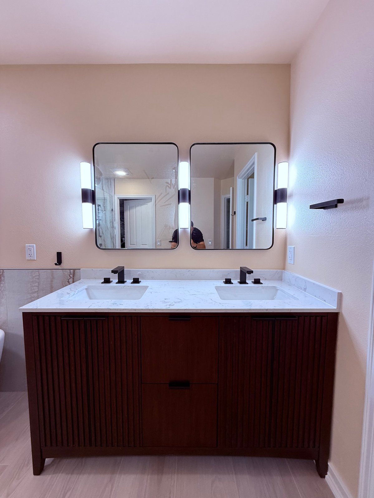 Modern bathroom vanity with dual sinks, marble countertop, and illuminated mirrors