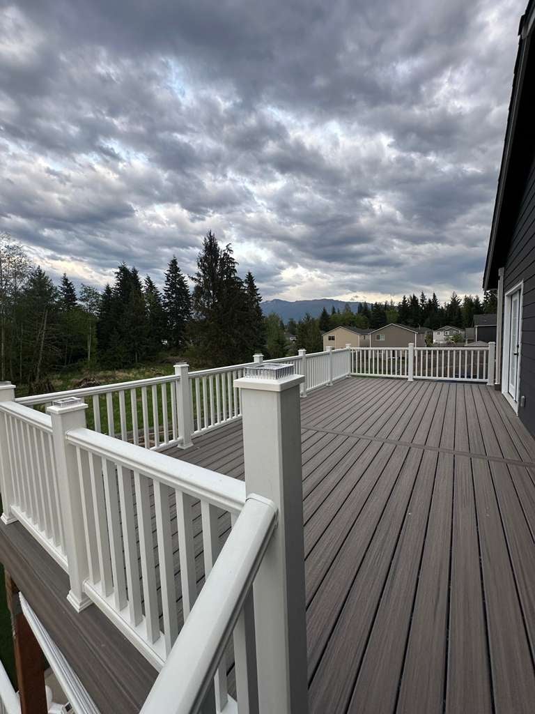 Large residential deck with white railings overlooking forested mountains