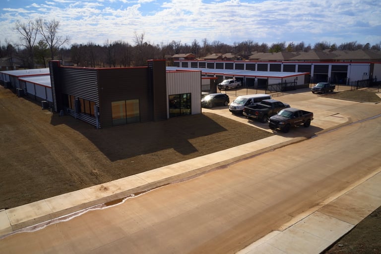 Aerial view of Locked Up Self Storage facility with metal and brick buildings, paved parking lot, and vehicles