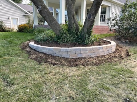 Curved stone retaining wall around large tree in front yard of residential home
